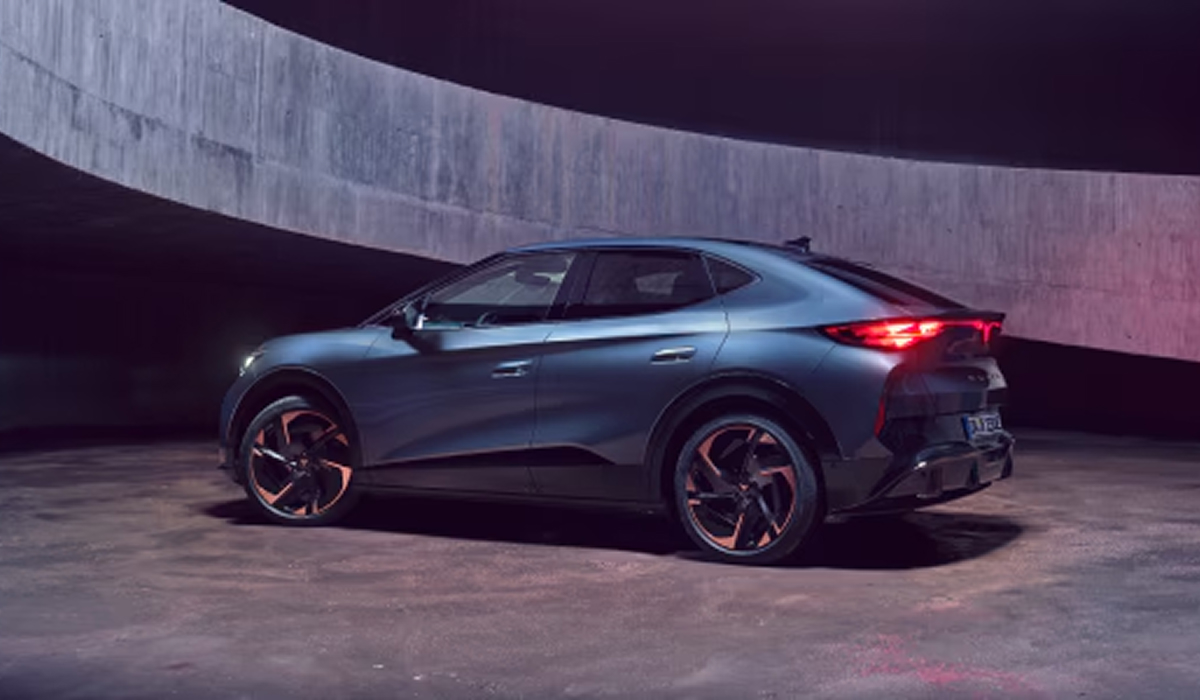 CUPRA Tavascan von schräg hinten in dunkler Umgebung, Betonwände im Hintergrund, Rücklichter rot leuchtend.